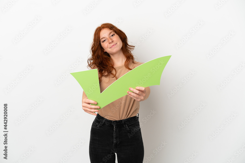 Teenager redhead girl isolated on white background holding a check icon with happy expression Teenager redhead girl isolated on white background holding a check icon with happy expression