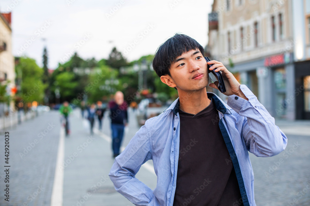 Asian male student tourist talking on phone outdoors Asian male student tourist talking on phone outdoors