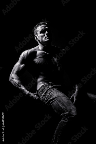 Sport workout bodybuilding concept. Handsome big muscles man posing at studio. Leather belt, jeans. Black and white