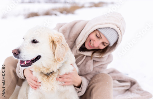 Young beautiful woman and her golden retriever dog having fun in winter. © Zhuravleva Katia