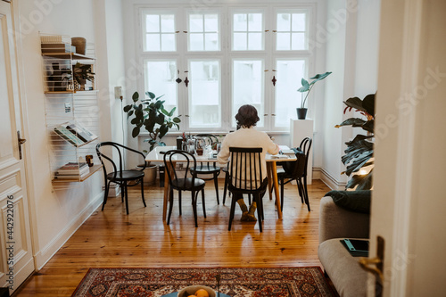 Manlig entreprenör sitter vid matbord och arbetar hemifrån photo