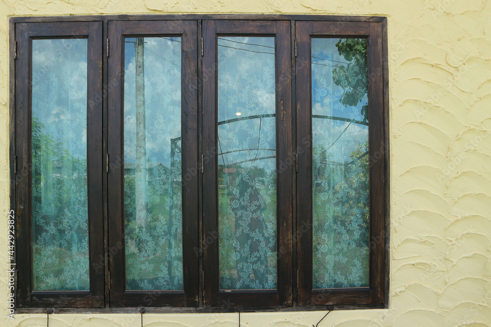 Fototapeta premium Large wooden window with beautiful curtains and yellow cement walls.