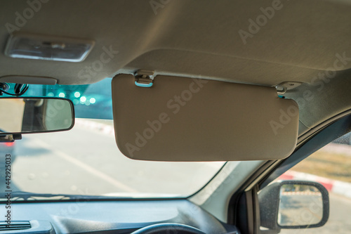 Car visor. Car interior. Grey open sun car visor with selective focus and car mirror on blurred background with automobile window
