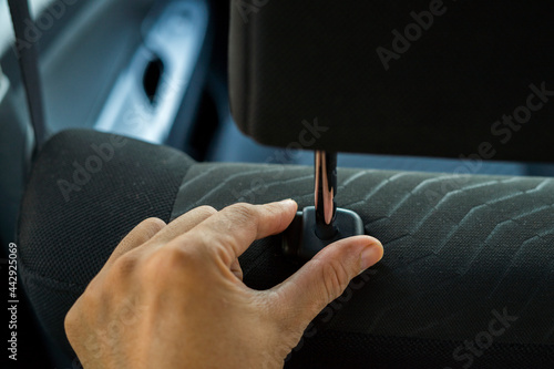 Hand adjusts headrest in car interior. adjusting the seat position in the car