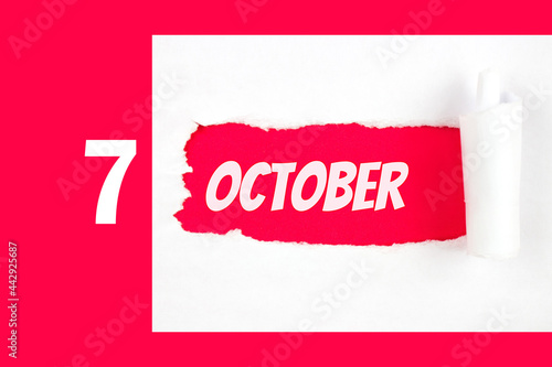 October 7th. Day 7 of month, Calendar date. Red Hole in the white paper with torn sides with calendar date. Autumn month, day of the year concept. photo