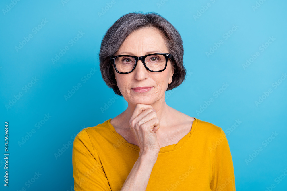 Close-up portrait of attractive content calm middle-aged woman touching chin isolated over vivid blue color background Close-up portrait of attractive content calm middle-aged woman touching chin isolated over vivid blue color background