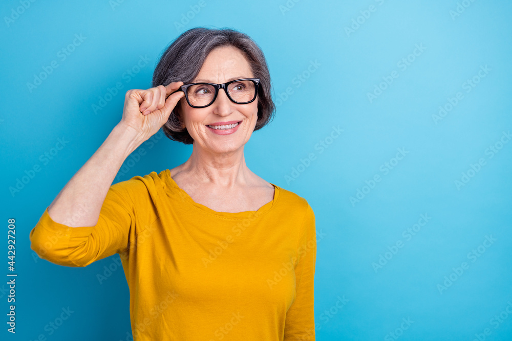 Portrait of attractive cheerful woman touching specs deciding copy space isolated over vivid blue color background