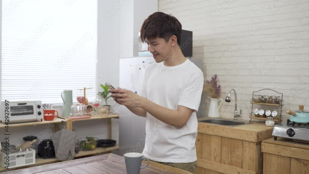 waist up happy male holding a mobile phone is having fun chatting with friends on social media apps in a bright home interior. waist up happy male holding a mobile phone is having fun chatting with friends on social media apps in a bright home interior.