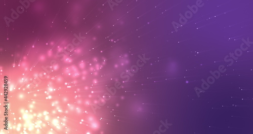 Glowing pink particles effervescing on a dark purple background photo