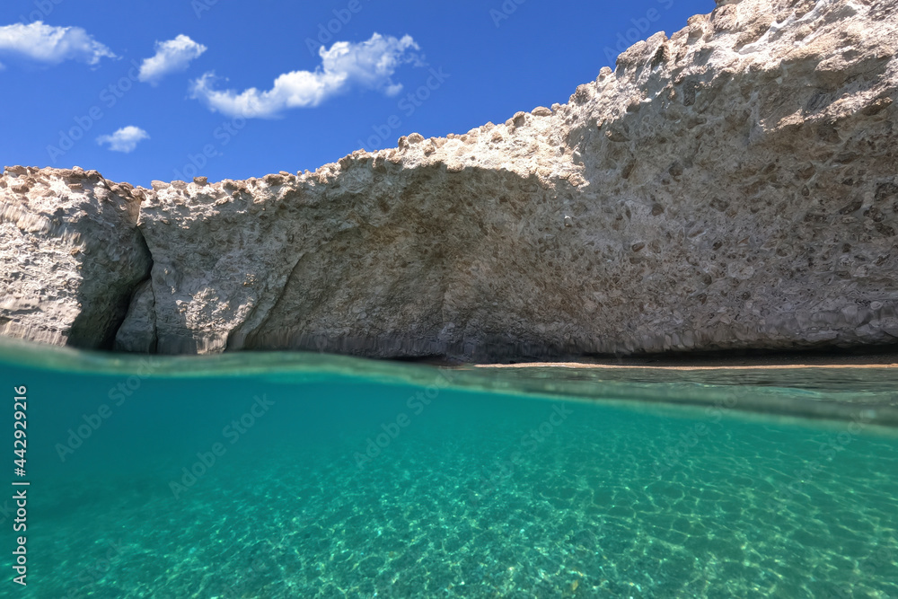 Underwater sea level split photo of iconic caves of Sarakiniko a geological volcanic white rock chalk resembling lunar scenery, Milos island, Cyclades, Greece