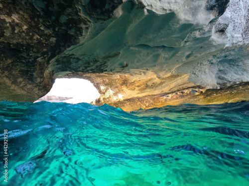 Underwater sea level split photo of iconic caves of Sarakiniko a geological volcanic white rock chalk resembling lunar scenery, Milos island, Cyclades, Greece