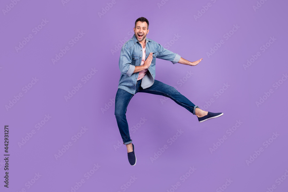 Full length body size photo man smiling jumping up practicing martial arts isolated pastel violet color background Full length body size photo man smiling jumping up practicing martial arts isolated pastel violet color background