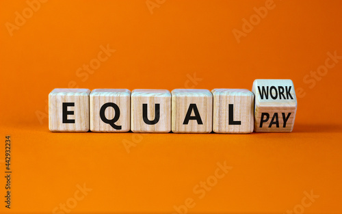 Equal pay and work symbol. Turned the wooden cube and changed words equal pay to equal work. Beautiful orange background. Copy space. Business and equal pay and work concept.