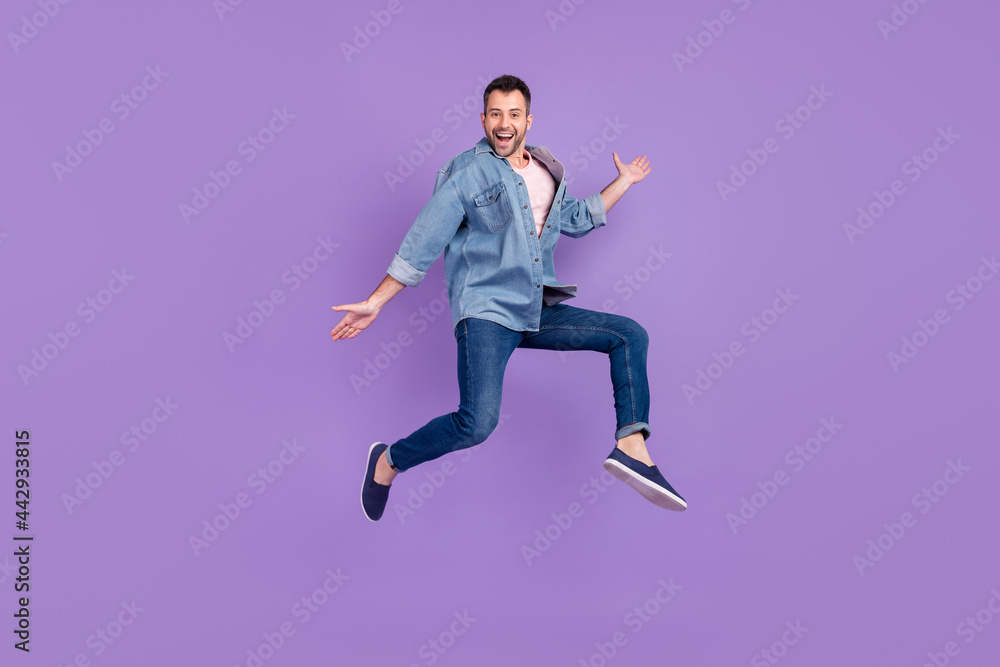 Full length body size photo man smiling jumping high laughing happy isolated pastel violet color background Full length body size photo man smiling jumping high laughing happy isolated pastel violet color background