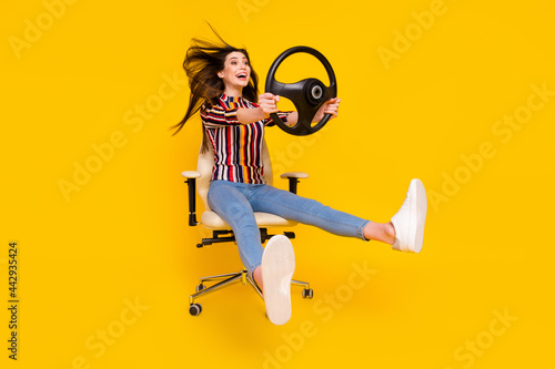 Full length body size photo girl sitting keeping steering wheel crazy imagine driving car isolated bright yellow color background