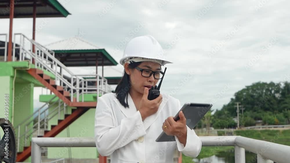 Female engineer in a white helmet working with a digital tablet and using radio communication at the dam construction site to generate electricity. Clean energy and Technology concepts. Female engineer in a white helmet working with a digital tablet and using radio communication at the dam construction site to generate electricity. Clean energy and Technology concepts.