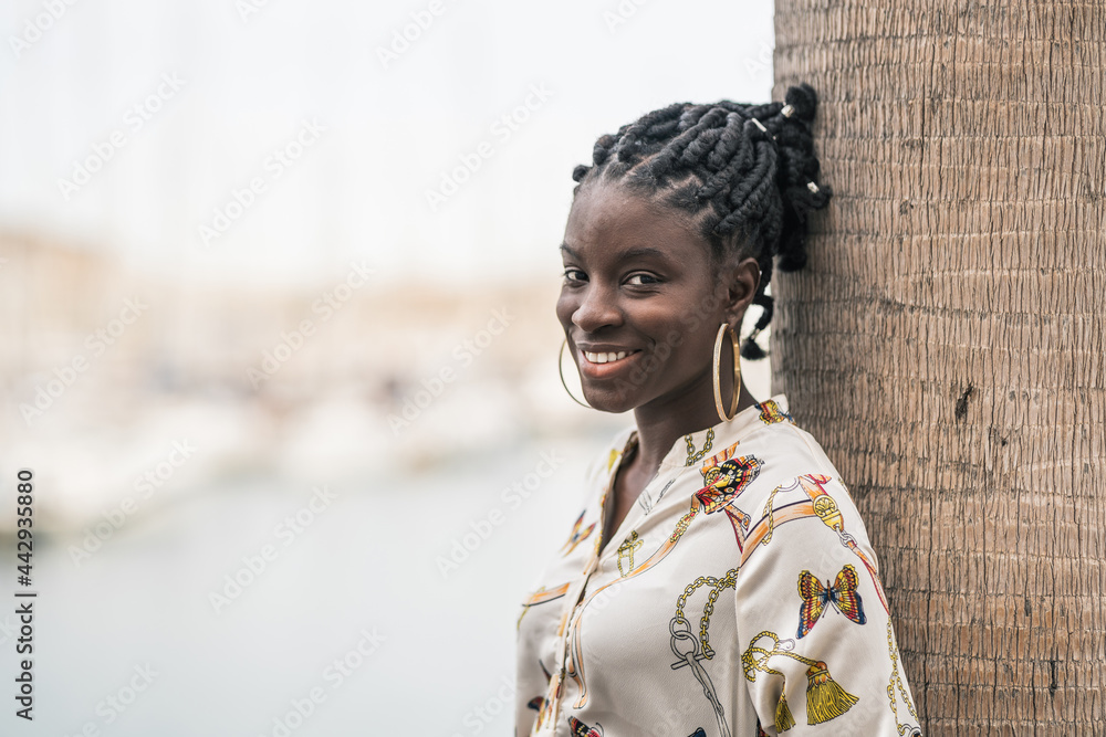 Happy black woman with ethnic braids and earrings looking at camera Happy black woman with ethnic braids and earrings looking at camera