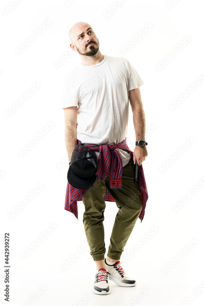Stylish young modern man in casual clothes looking up with skeptical expression. Full body portrait isolated on white background Stylish young modern man in casual clothes looking up with skeptical expression. Full body portrait isolated on white background