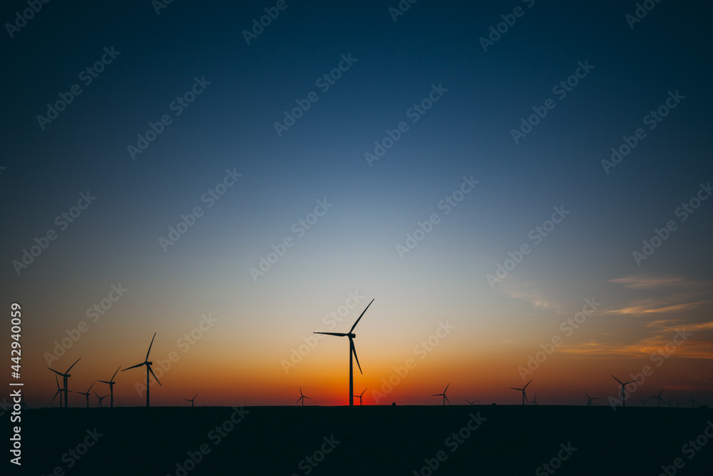Wind Turbines producing renewable energy at sunset 