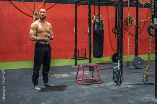 Strong sportsman looking away in gym