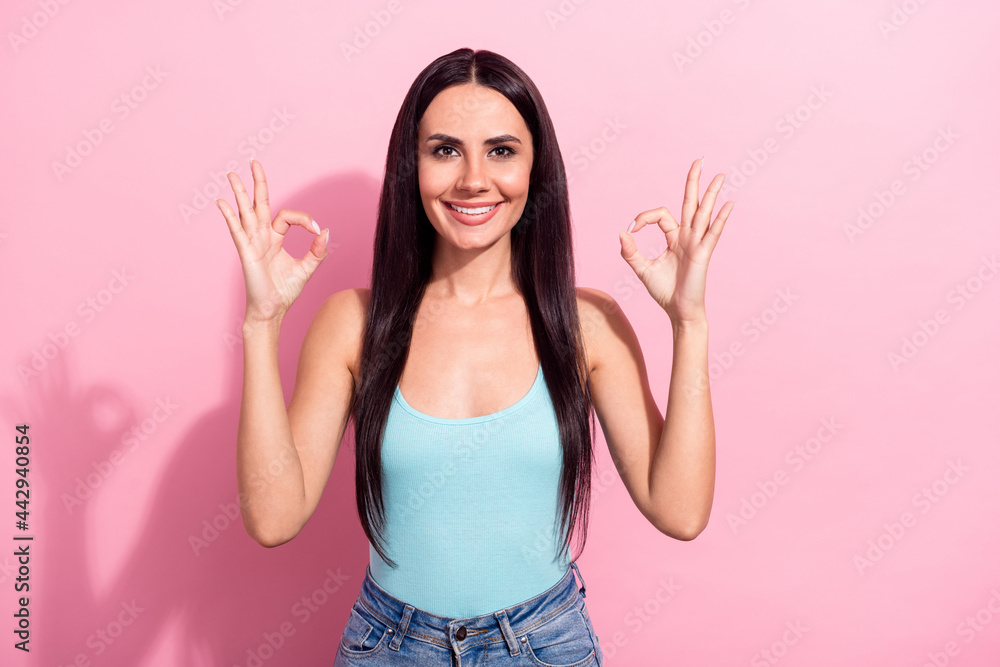 Photo portrait pretty brunette in blue singlet showing okay gesture isolated pastel pink color background Photo portrait pretty brunette in blue singlet showing okay gesture isolated pastel pink color background