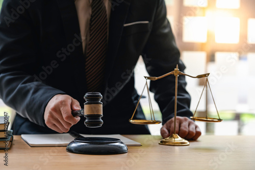 Man holds gavel judge with a lawyer, Judge with gavel at a wooden table indoors, closeup, the hammer in the hand of the judge. Criminal law