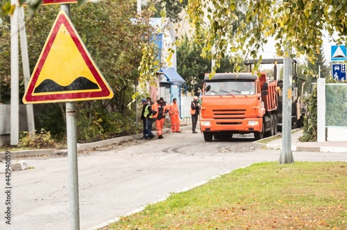 Laying of asphalt. Road sign "Speed bump" and special equipment