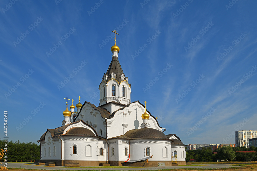 Stone white church of Holy Apostles Constantine and Elena against background of beautiful blue sky with clouds. Moscow, Russia