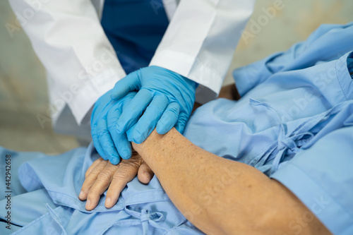 Doctor holding hand and checking Asian senior or elderly old lady woman patient wearing a face mask in hospital for protect infection Covid-19 Coronavirus.