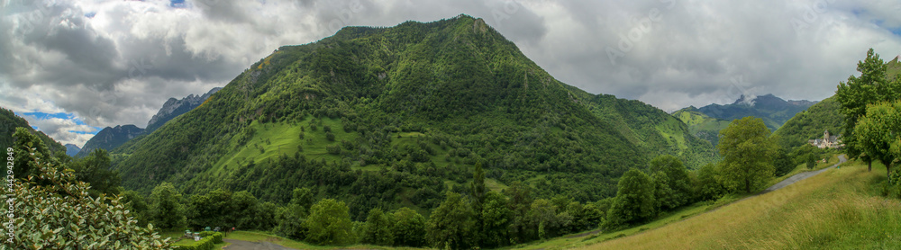 Paisaje natural de Cette-Eygun, un pequeño pueblo en el lado norte de los Pirineos franceses. Hermosas laderas verdes al final de la primavera en un día nublado. Francia.