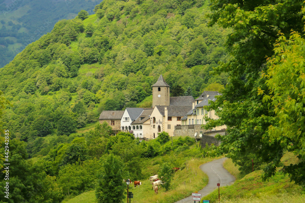 Cette-Eygun, un pequeño pueblo del lado francés de los Pirineos. Paisaje rural de un pequeño pueblo encajado en un valle entre bosques y empinadas montañas. Iglesia de San Pedro al fondo.