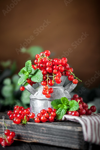 Fresh red currants in a Cup on a dark rustic wooden table. Background with space for copying. Selective focus.