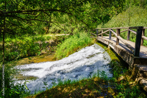 Small waterfall under a wooden bridge at the source of the Ebro river. Fontibre Cantabria.