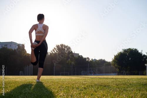 A young, beautiful, dark-haired woman with a short haircut and an athletic build exercises in the park in the early morning. Healthy lifestyle concept. Yoga