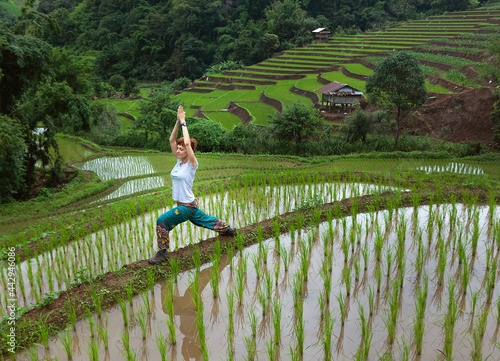 Serene woman practicing yoga on verdant rice fields photo