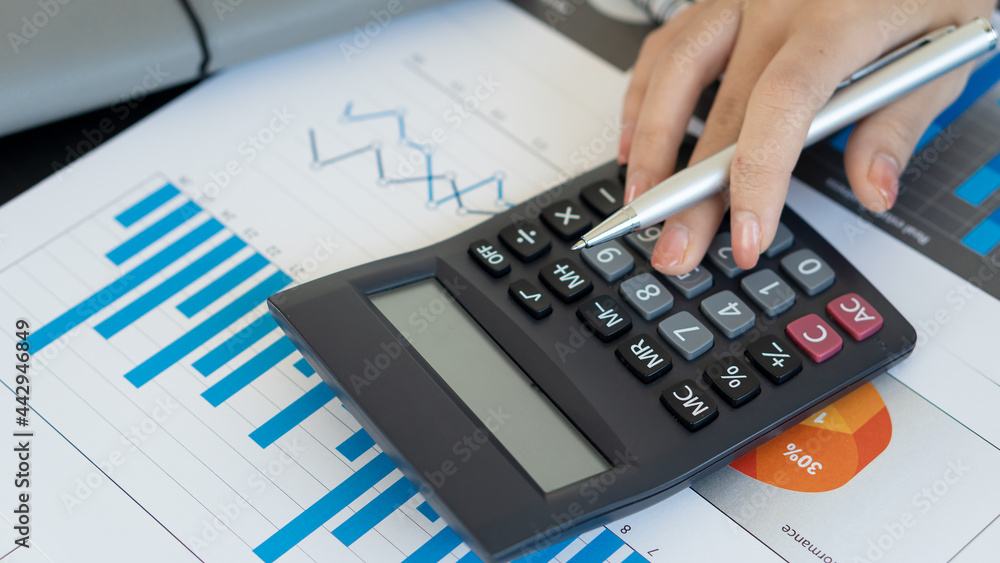 Business people work with graphs and laptop calculators to analyze the company's profitable costs with taxes and finance. Business people work with graphs and laptop calculators to analyze the company's profitable costs with taxes and finance.
