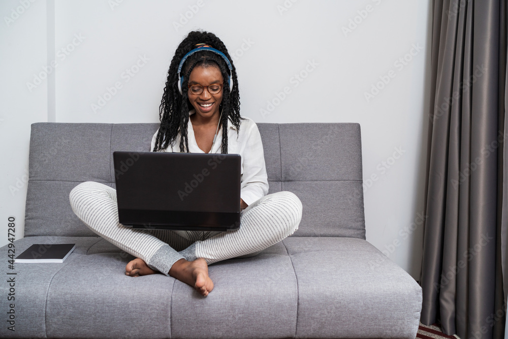 © ADDICTIVE STOCK - Concentrated young ethnic lady in headphones working distantly on netbook at home © ADDICTIVE STOCK - Concentrated young ethnic lady in headphones working distantly on netbook at home