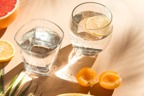 water glasses  with fruit on sunlight close up, fresh and healthy summer drinks beige color background  photo