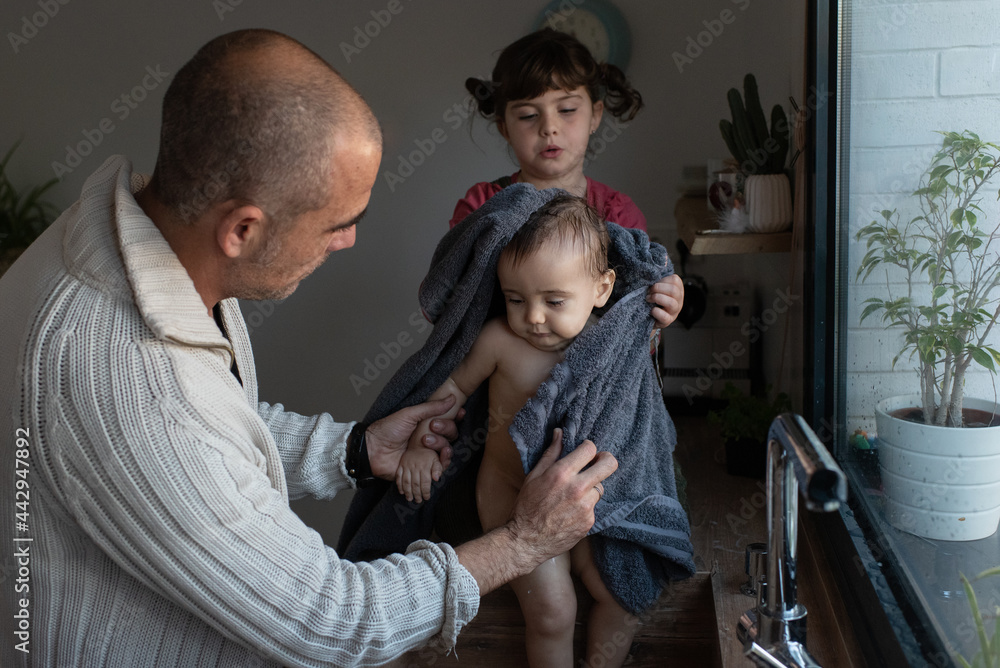 Father and daughter wiping baby with towel Father and daughter wiping baby with towel