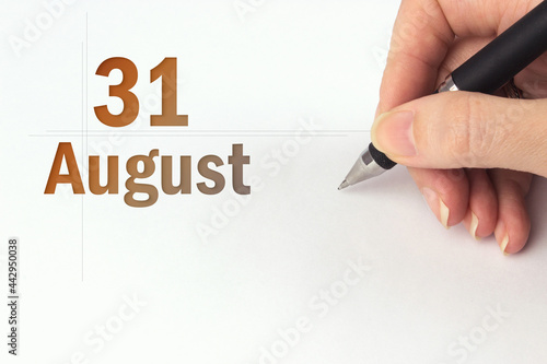 August 31st . Day 31 of month, Calendar date. The hand holds a black pen and writes the calendar date. Summer month, day of the year concept. photo