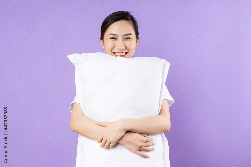 Asian woman holding upper pillow, isolated on purple background Asian woman holding upper pillow, isolated on purple background