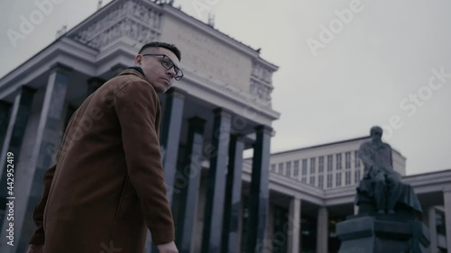 Wallpaper Mural Businessman in eyeglasses near library. He's wearing a brown long coat. Man walking on urban street in slow motion. The Russian State Library is national library of Russia Torontodigital.ca