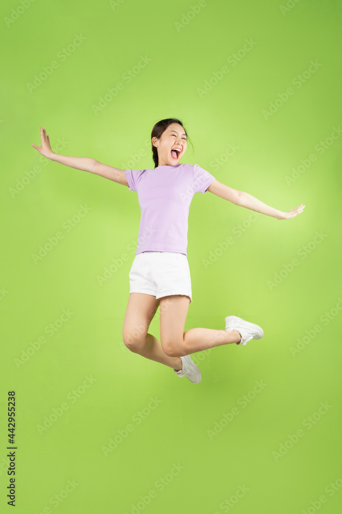Full body Young Asian girl jumping, isolated on green background