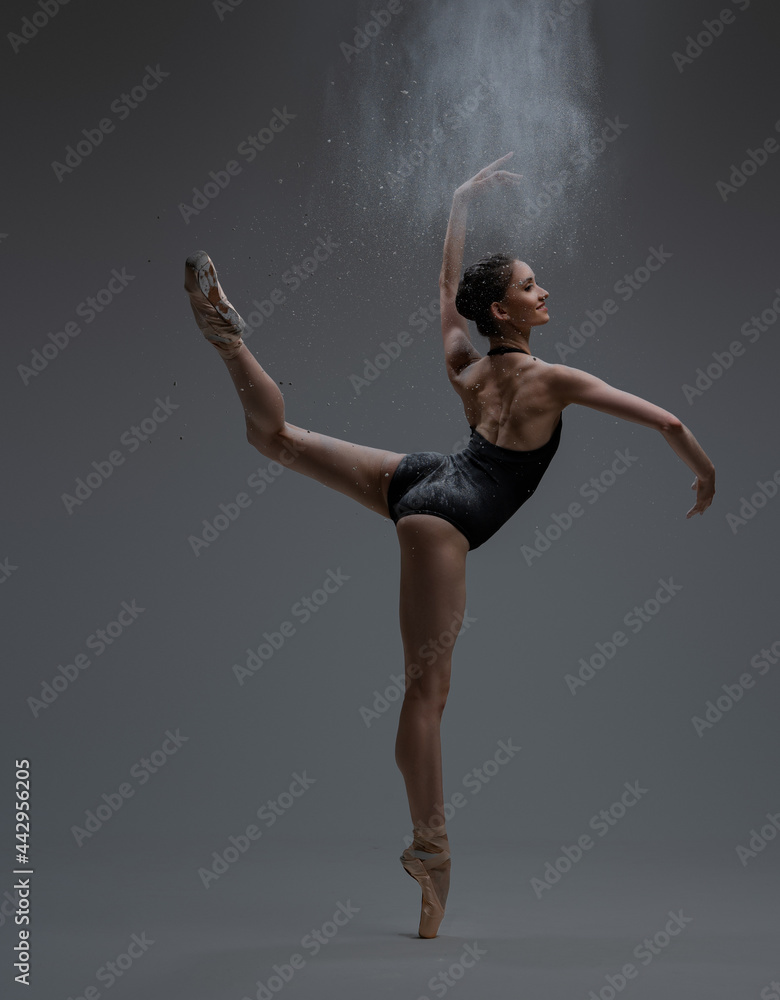 Graceful ballerina spraying dust and dancing inside studio