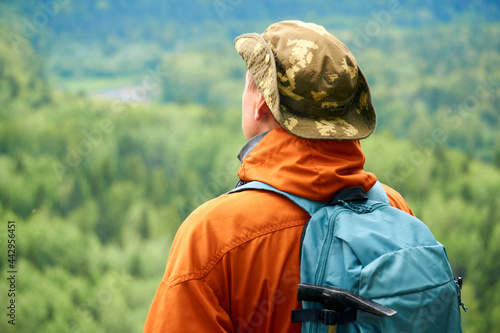 male traveler looking into the distance against the backdrop of a wooded mountain landscape