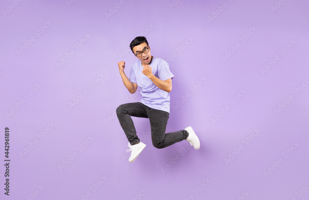 Portrait of a jumping asian man, isolated on purple background