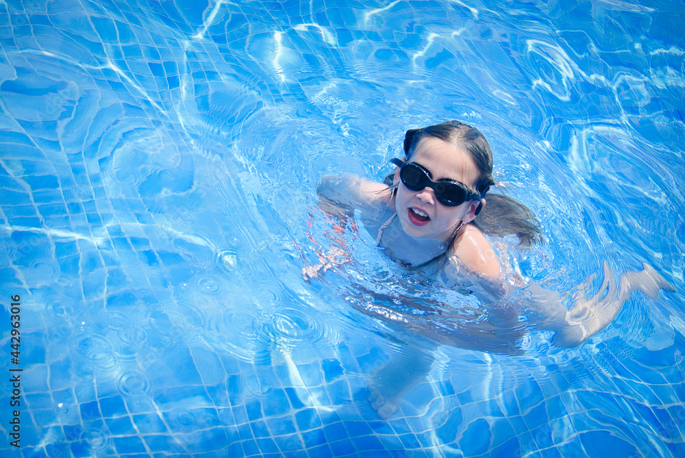 Naklejka premium Active young girl swimming pool with goggles on her face