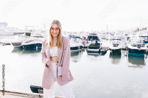Portrait of a cheerful happy emotional elegant young woman enjoying traveling walking along the pier among boats and yachts outdoors © Елизавета Старкова