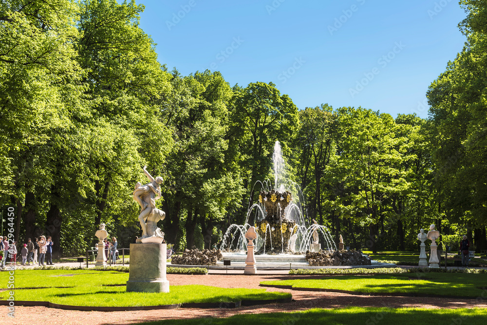 View of the Summer Garden in St. Petersburg with a crown fountain, sculptures and walking tourists. Saint Petersburg, Russia