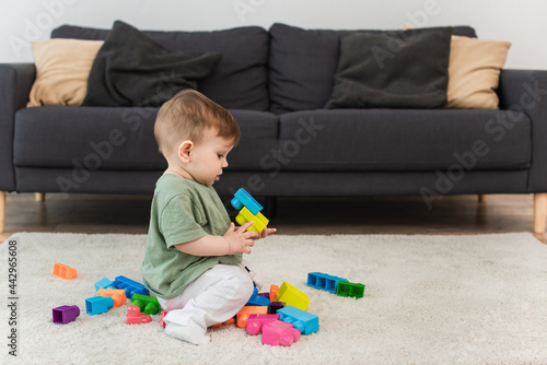 Side view of toddler boy playing building blocks on carpet